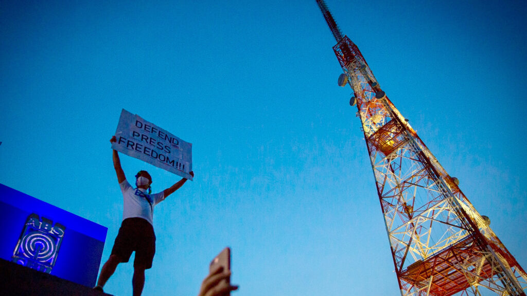 Protestor standing next to a transmission tower